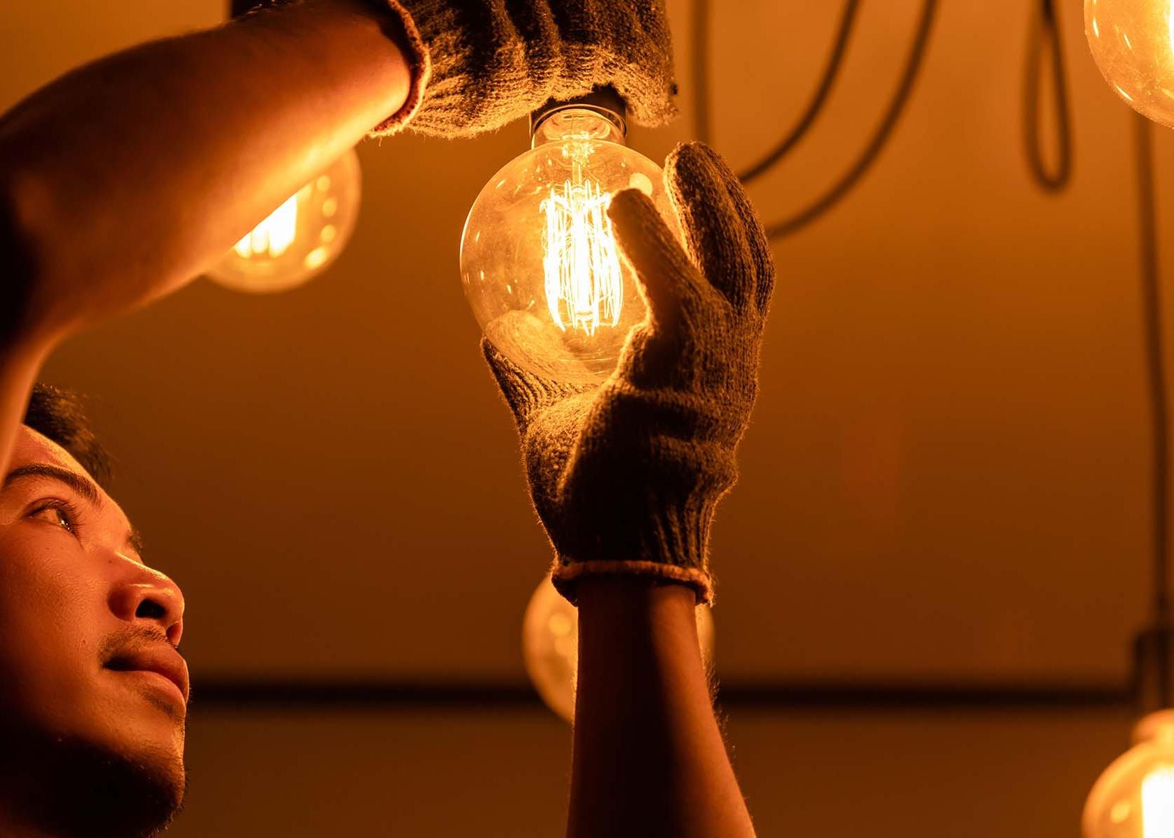 一个戴着手套的人正在换一个发光的灯泡